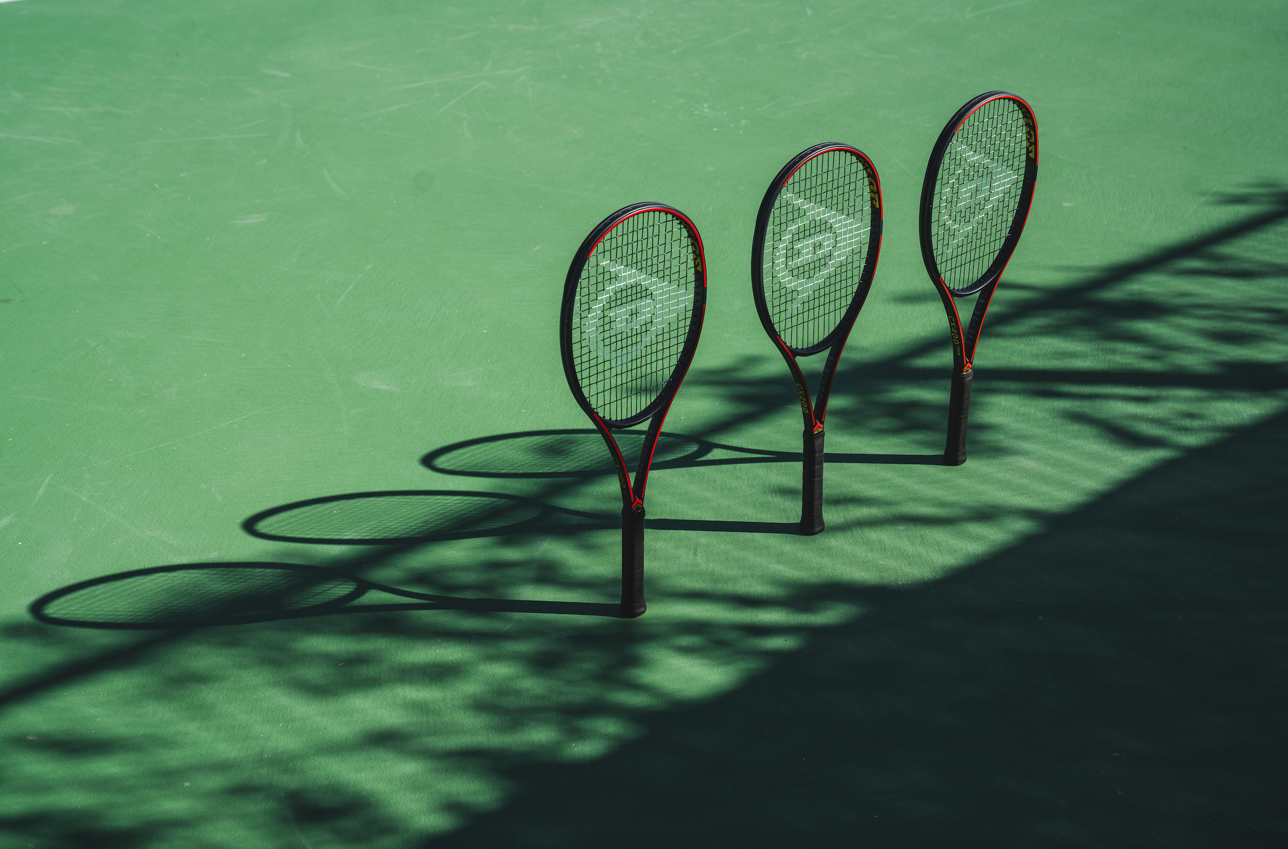 Três raquetes de ténis Dunlop em court verde